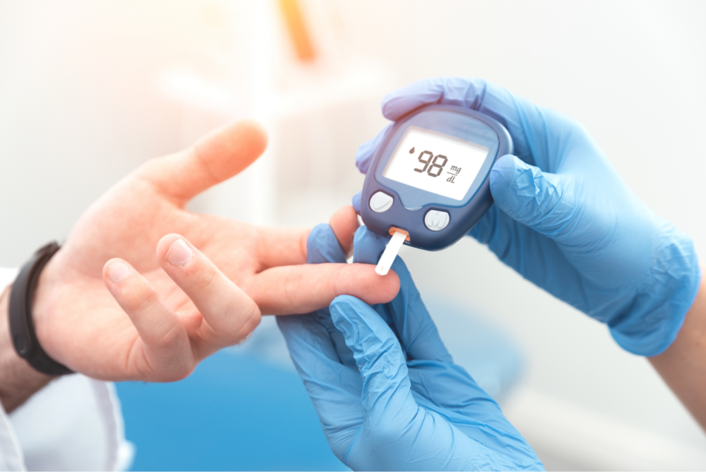 Close-up of a blood sugar test with a glucose meter reading 98 mg/dL, emphasizing diabetes awareness during National Diabetes Month.