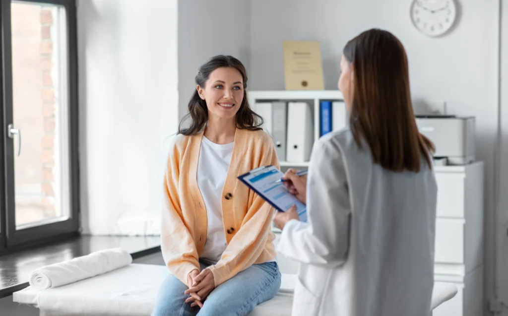 A patient smiling while consulting with a doctor about her health during a primary care physical.