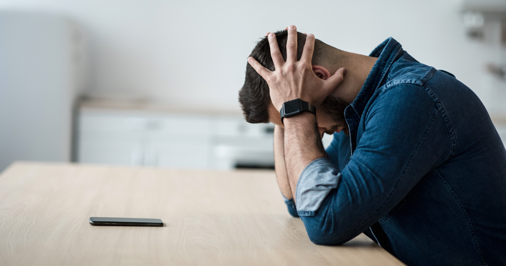 Man showing stress while sitting alone for Mental Health Awareness Month.