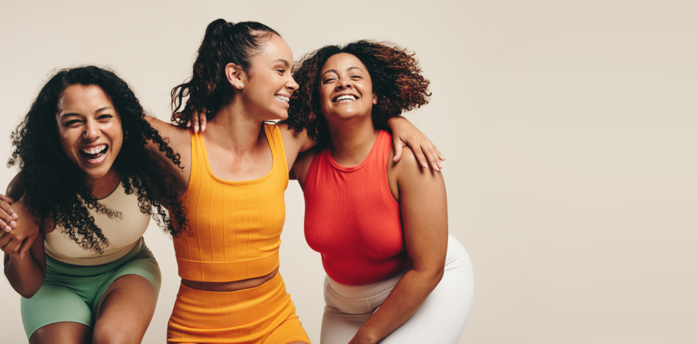 Happy women embracing and laughing in activewear for Women's Health Month.