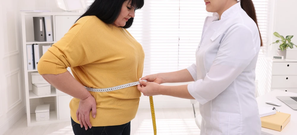 Wellness professional measuring a patient's waistline to track progress for National Wellness Month.