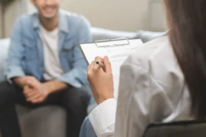 Healthcare provider holding a clipboard while speaking with a seated patient