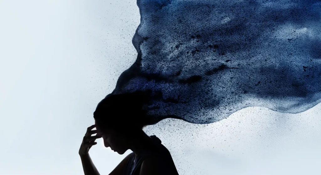 Silhouetted person holds a hand to their forehead beneath a large dark blue textured abstract shape.