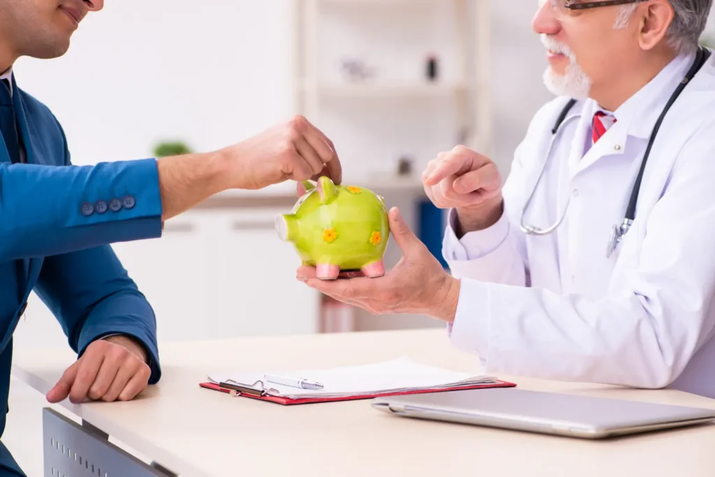 Doctor holding a green piggy bank while a man in a blue suit reaches toward its top slot across a desk.